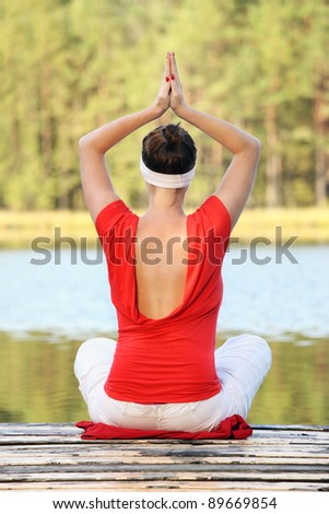 A picture of a young woman practicing yoga over natural green background