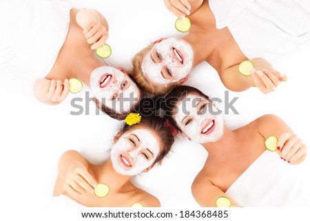 A picture of four friends enjoying their time in spa with facial masks over white background