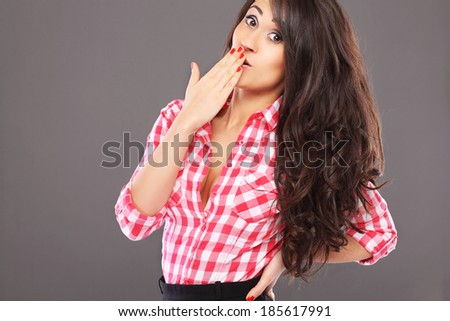 Surprised young woman over grey background in shirt