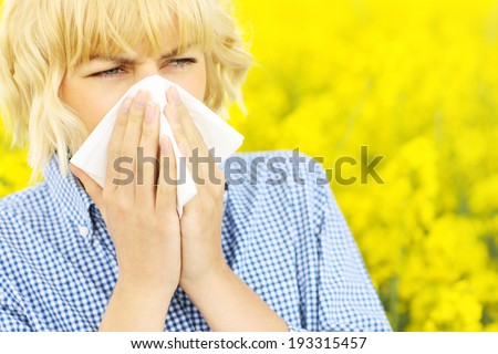 A portrait of a sneezing woman over a yellow field of flowers