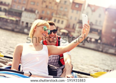 A picture of a young couple taking pictures in a canoe