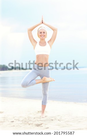 A picture of a woman in a yoga position on the beach