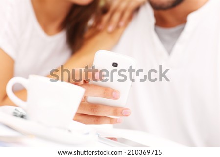 A closeup of hands and smartphone in a cafe
