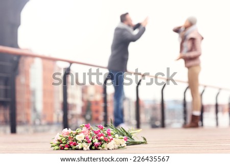A picture of lost flowers and a couple arguing in the background