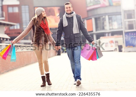 A picture of cheerful young people walking with shopping bags in the city