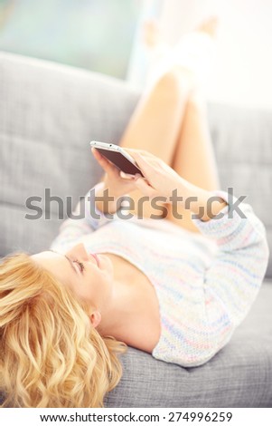 A picture of a sexy woman lying on sofa and using smart phone