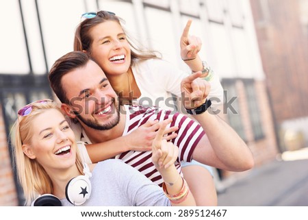 A picture of a group of happy friends smiling to the camera and pointing at copy space