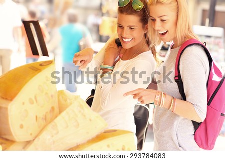 A picture of two tourists shopping for cheese on a food market