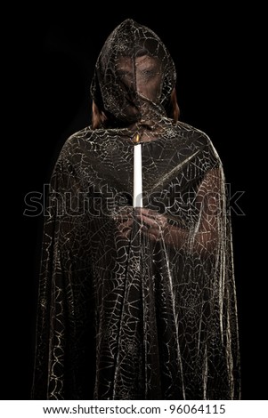 A picture of a mysterious person standing against dark background with a candle