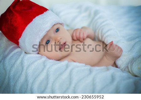 adorable cute baby girl in red christmas hat laying covered with white blanket on white background