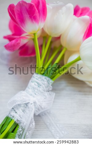 spring flowers tulips bouquet pink and white with lace ribbon laying on wooden background present for holidays mother woman day valentines easter