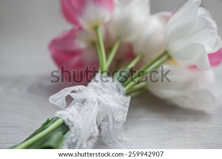 spring flowers tulips bouquet pink and white with lace ribbon laying on wooden background present for holidays mother woman day valentines easter