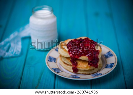 fresh natural healthy bottle with milk product and lace decoration plate with pancakes and raspberry jam on blue wooden background