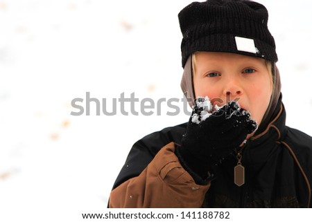 8 year old boy outside eating snow.