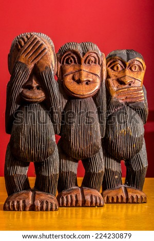 See hear speak no evil carved wooden monkeys on red background full body facing front