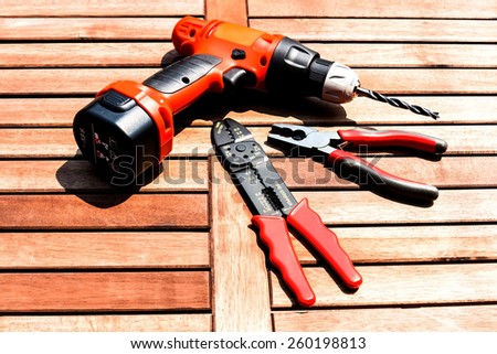 Background image of drill driver, wire stripper and pliers on the wood table