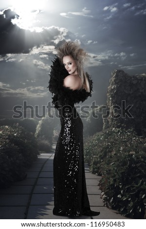 Elegant woman in long black dress at mystic garden