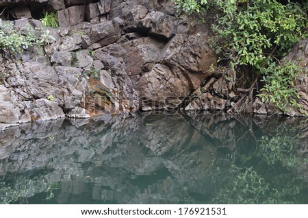 Natural scenery photograph of big stone rock and its reflection in blue color water pond, perfect natural backdrop