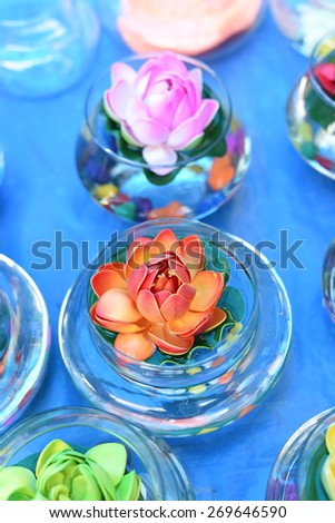 Pretty, bright and beautiful colors of plastic flowers in water filled flasks in soothing blue light setting