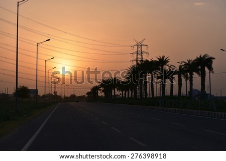 Gurgaon, India  urban road and High-voltage tower power wires with sunset and sky background