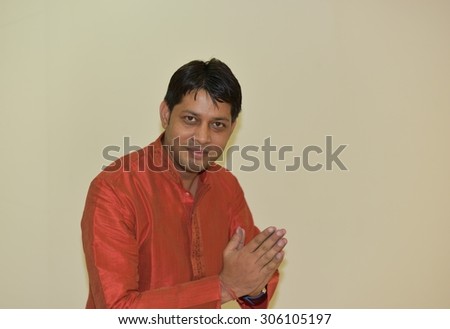 Close up portrait of Young Indian Man wearing Ethnic Indian Dress, Man is welcoming by joining his hands, Indian Style Welcoming gesture known as Namaste, lot of space for text messages in the picture