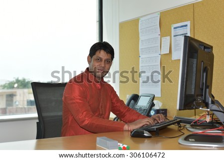 Close up portrait of Young Indian Man wearing Ethnic Indian Dress and working in high tech office on computer, India is leading in software development & other technology related business