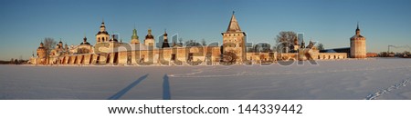 Fortifications of the Kirillo-Belozersky Monastery in the rays of the setting sun on a frosty winter day with ice Siverskoye lake.