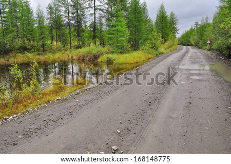 Photo dirt road after the rain in the Yakut taiga at the end of summer. Oymyakon highlands, a ridge of Suntar-khayata, between lake Ulu mosque and the river Suntar.