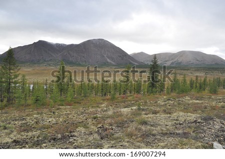 Autumn tundra on the background of mountains in Yakutia. Cloudy landscape in the route area \