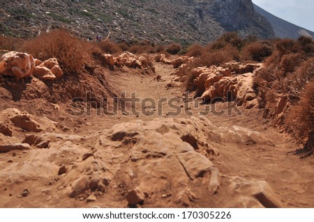 Red dusty road in the mountains on the Greek island. Mediterranean sea, the island of Crete. Greece.