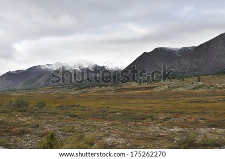 Autumn tundra on the background of mountains in Yakutia. Cloudy landscape in the route area \