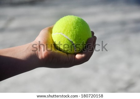 Yellow tennis ball, illuminated by the sun, in a child\'s hands.