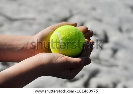 Yellow tennis ball, illuminated by the sun, lies in a child\'s hands.