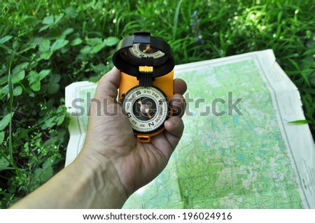 Forest, may, walk in the woods. Compass in hand, against the background of the map.