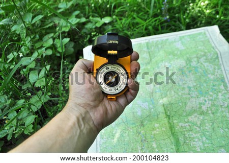 Forest, may, walk in the woods. Compass in hand, against the background of the map.