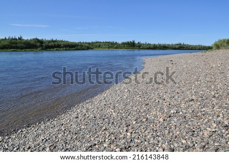 Pebble beach North of the river. Summer landscape of one of the rivers of the Northern slope of the Polar Urals.