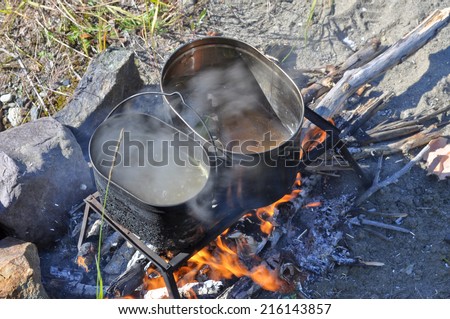 Cooking fish on the fire. Tourist fire, trivet, and two pot that cooked fish soup.
