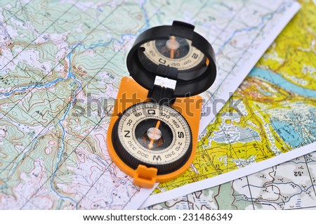 Compass, map, outdoor. The magnetic compass is located on the topographic map.