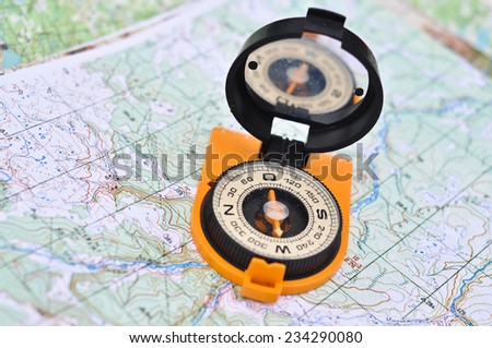 Compass, map, outdoor. The magnetic compass is located on the topographic map.