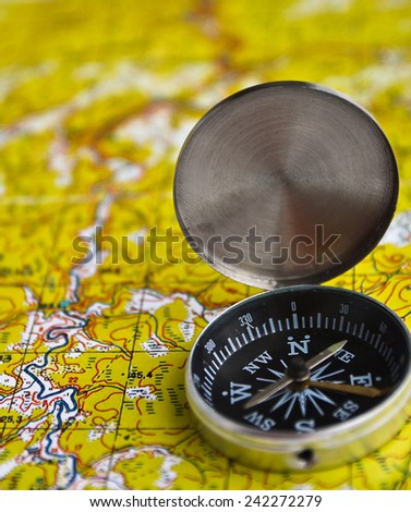 The magnetic compass is located on a topographic map. Satellites adventure - map and compass.