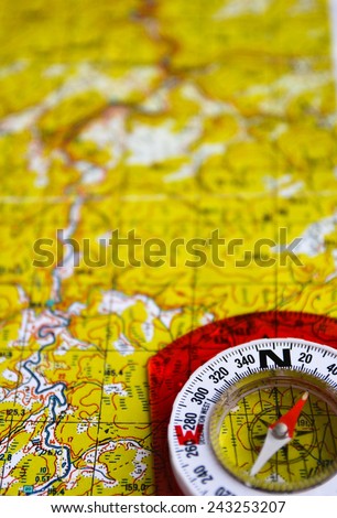 The magnetic compass is located on a topographic map. Equipment for travel - map and compass.