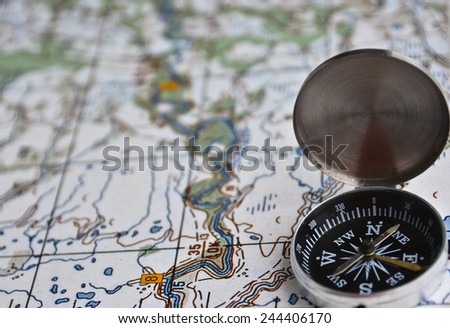 The magnetic compass is located on a topographic map. Satellites adventure - map and compass.