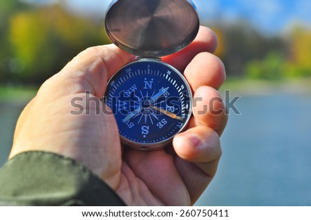 Walking with a compass in his hand. Open the magnetic compass in hand on the autumn landscape.