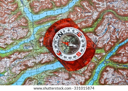 Magnetic compass is located on a topographic map. Navigation: a compass and a map.