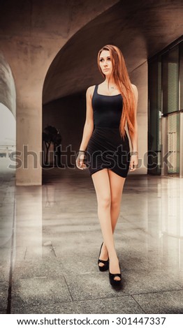 Red-haired girl model walks in a modern architectural place.