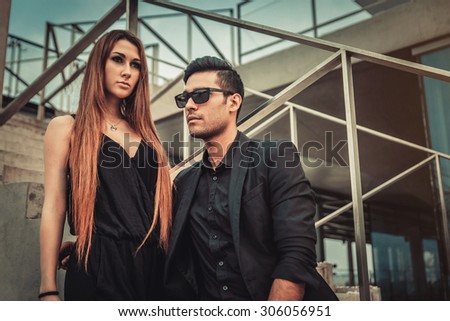 Young and trendy man and woman models sitting near stairs. Fashion Style