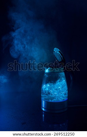 Boiling kettle with steam in blue light