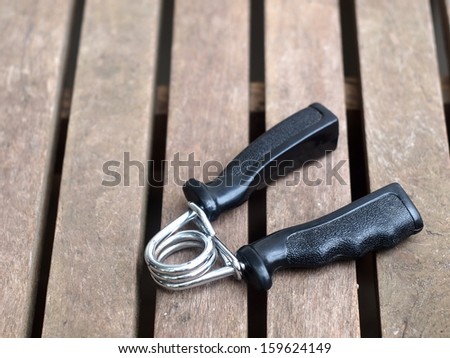 black hand grip exercise finger training equipment on an old wood table