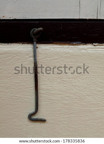 old rusty small metal windows hook in original vintage retro style house fitted on a dark painted wood window frame