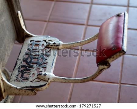 foot rest of an old retro vintage chair metal white with red leather close up in a haircut barber shop